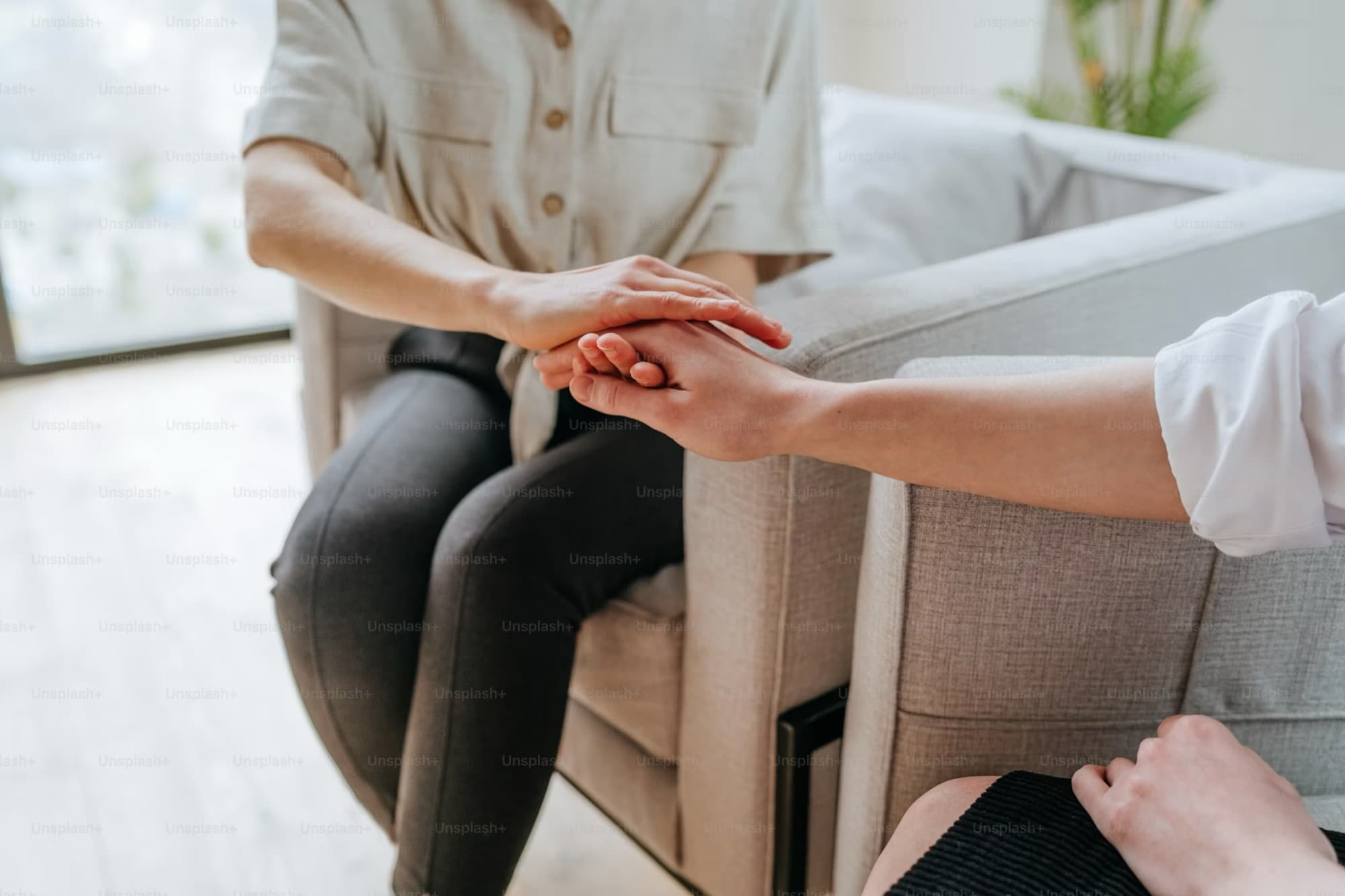 A therapist resting a reassuring hand on a client's hand during a session